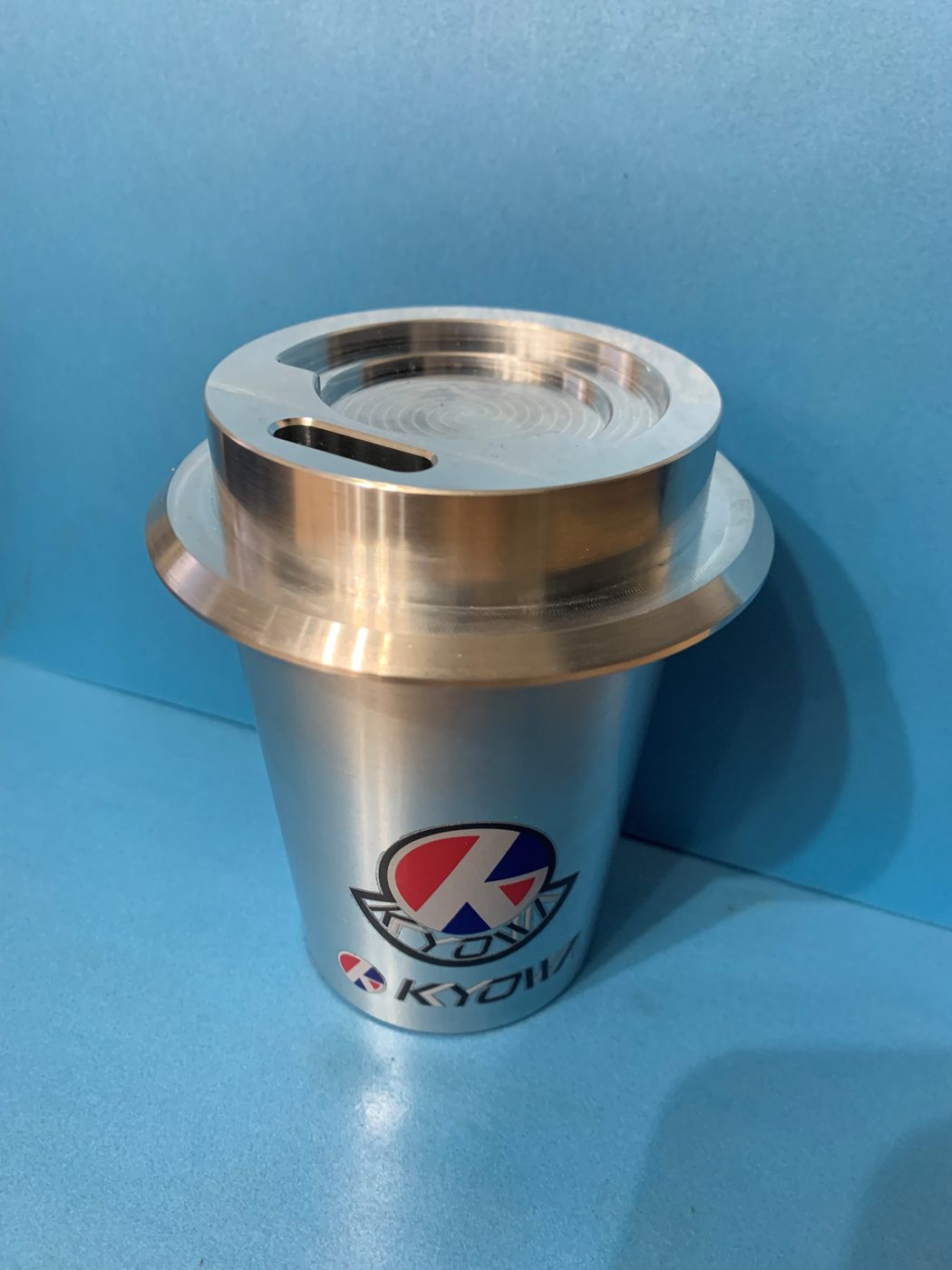 削り出しで製作したオリジナルコーヒーカップ。本体に協和精機のロゴが入り、上部に金属製の蓋が載っている。